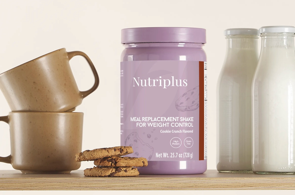 Nutriplus meal replacement shake container with mugs and cookies on a wooden surface